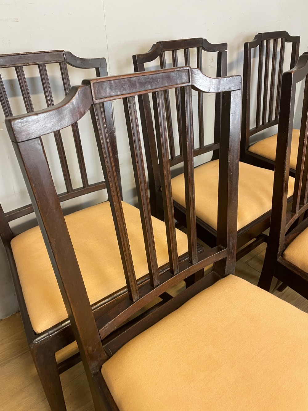 A set of six late Georgian dark mahogany country-made dining chairs featuring vertical bar backs and padded light tan upholstered drop-in seats. View V