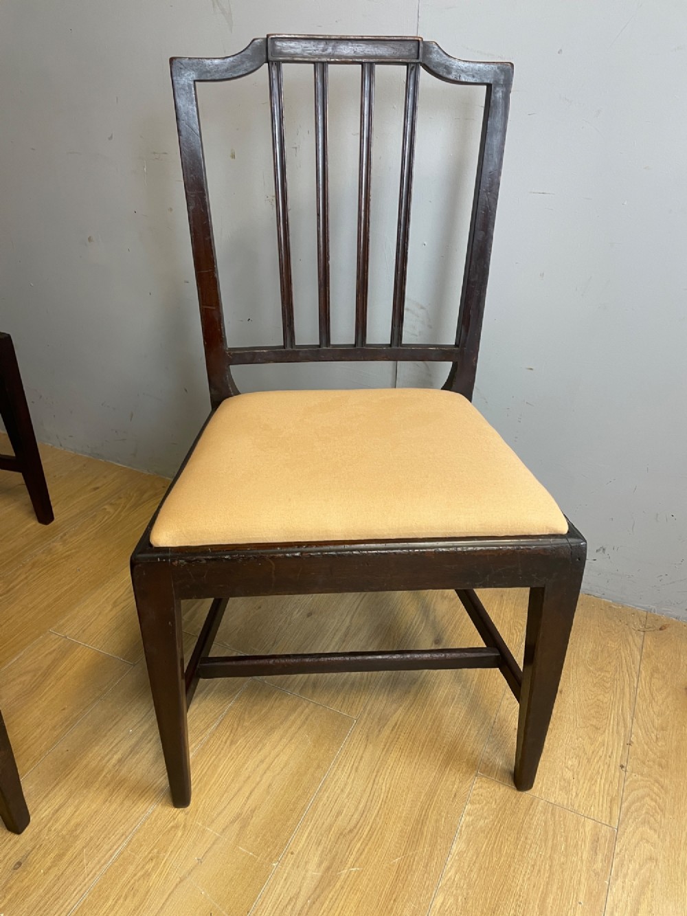 A set of six late Georgian dark mahogany country-made dining chairs featuring vertical bar backs and padded light tan upholstered drop-in seats. View VI