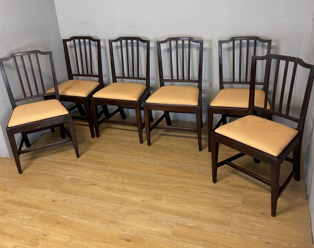 A set of six late Georgian dark mahogany country-made dining chairs featuring vertical bar backs and padded light tan upholstered drop-in seats. View XIII
