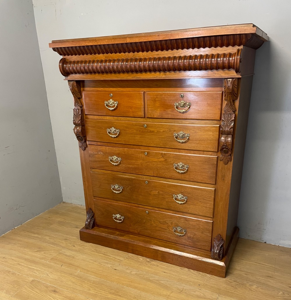 A 19th-century Scottish walnut chest of drawers featuring carved acanthus corbels, a gadrooned top frieze, and ornate brass drop handles. View II
