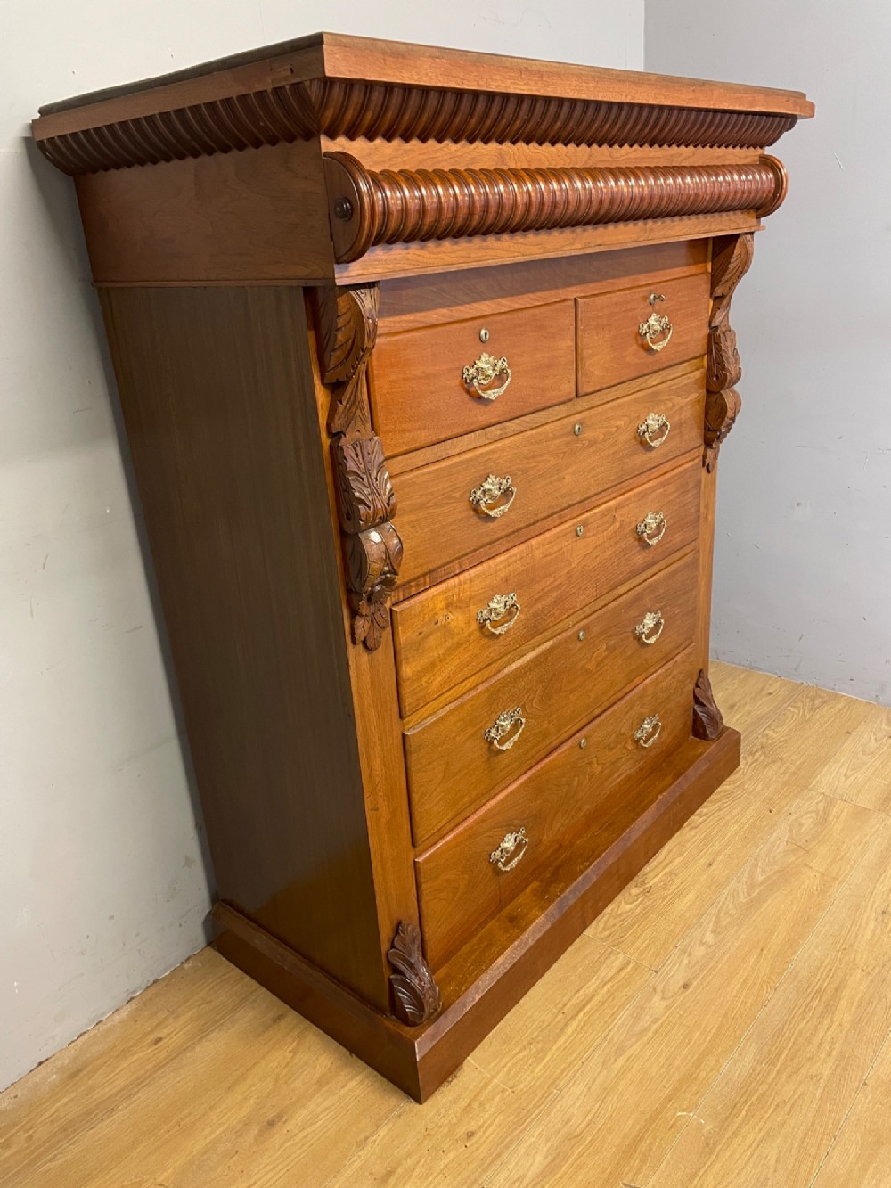 A 19th-century Scottish walnut chest of drawers featuring carved acanthus corbels, a gadrooned top frieze, and ornate brass drop handles. View IV