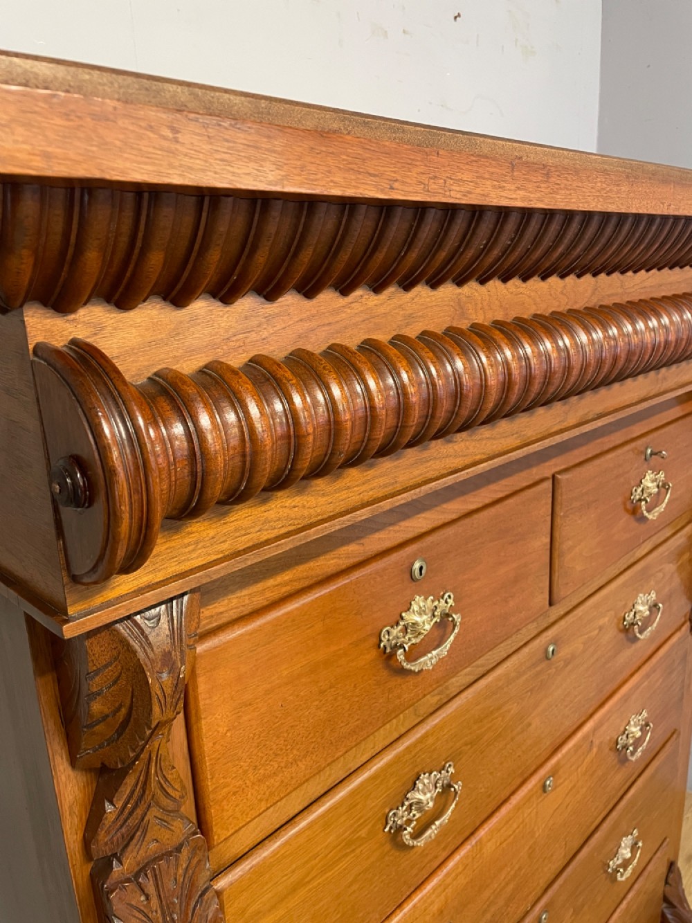 A 19th-century Scottish walnut chest of drawers featuring carved acanthus corbels, a gadrooned top frieze, and ornate brass drop handles. View V