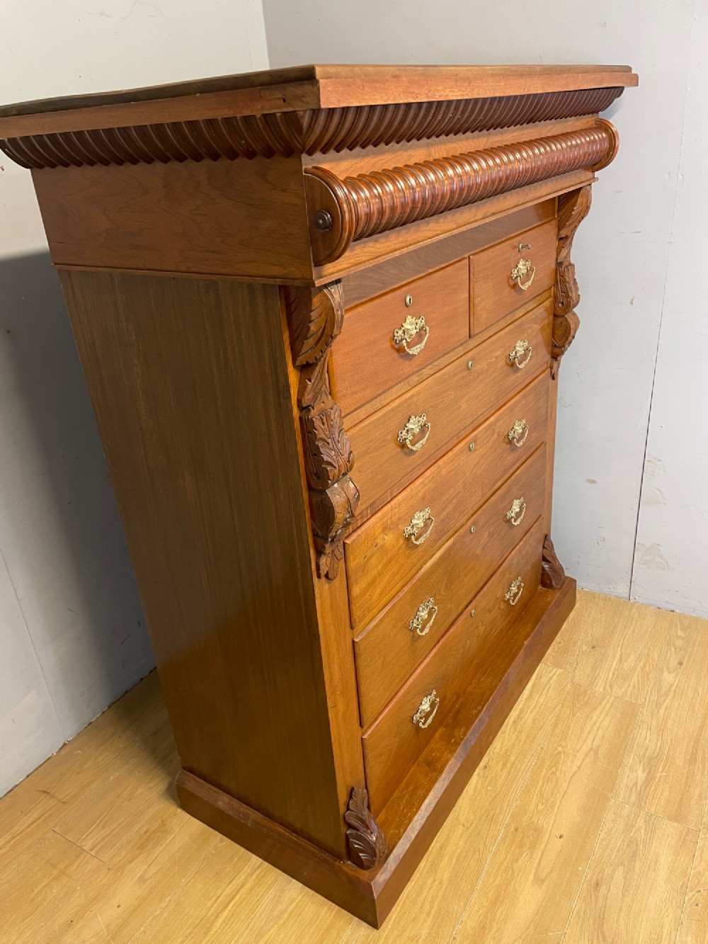 A 19th-century Scottish walnut chest of drawers featuring carved acanthus corbels, a gadrooned top frieze, and ornate brass drop handles. View XII