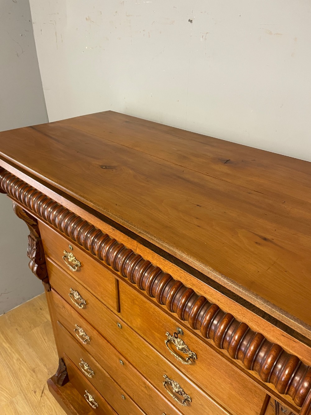 A 19th-century Scottish walnut chest of drawers featuring carved acanthus corbels, a gadrooned top frieze, and ornate brass drop handles. View XIII