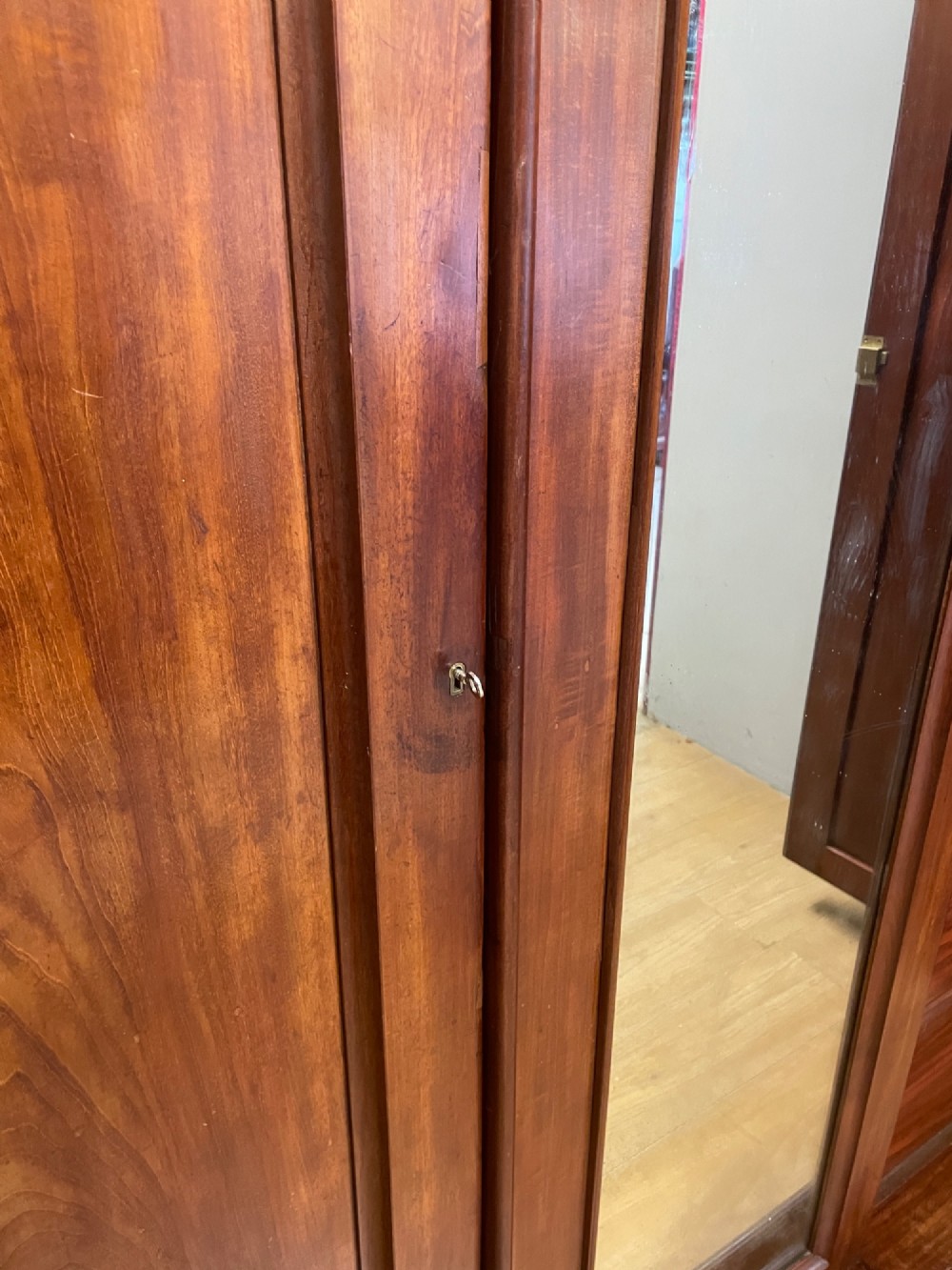 A 19th-century flame mahogany triple wardrobe with an arched central mirrored door flanked by two panelled doors, topped with a stepped cornice and carved corbels. View VIII