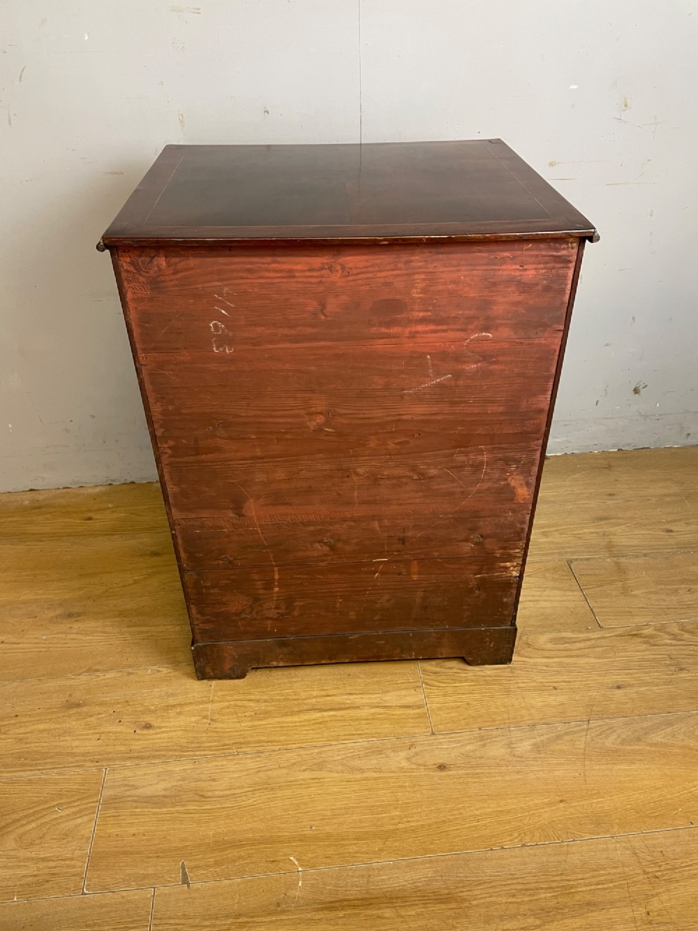 A Georgian mahogany side cabinet featuring oval flame veneer inlaid cupboard doors above two drawers with brass handles, resting on bracket feet. View X