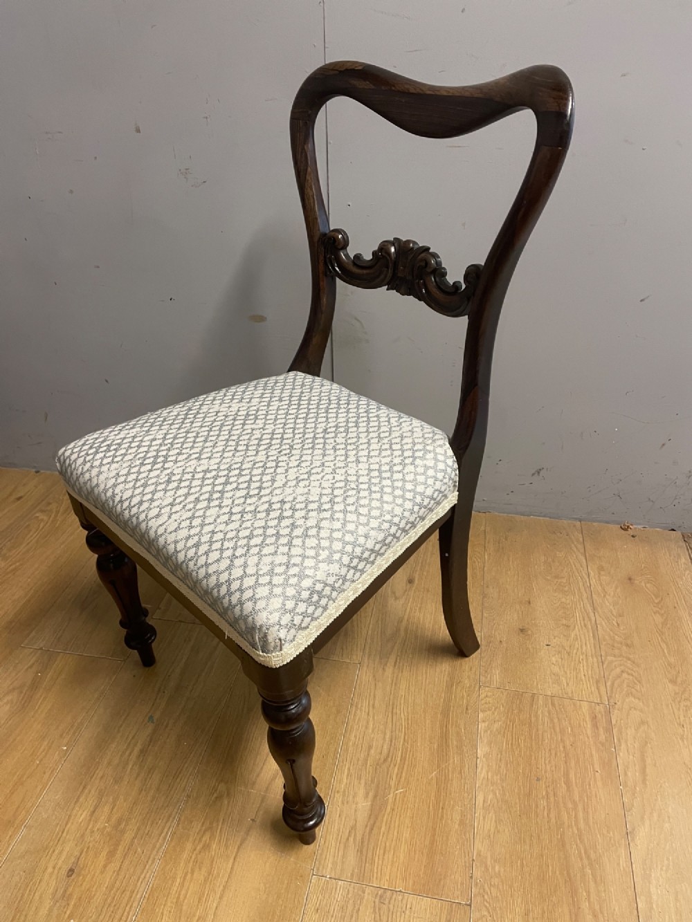 A set of four Victorian rosewood balloon back dining chairs with carved mid-rails, turned front legs, and grey patterned upholstered seats. View IV