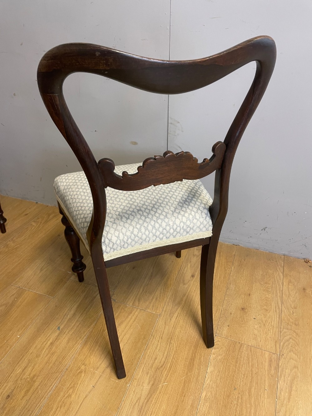 A set of four Victorian rosewood balloon back dining chairs with carved mid-rails, turned front legs, and grey patterned upholstered seats. View V