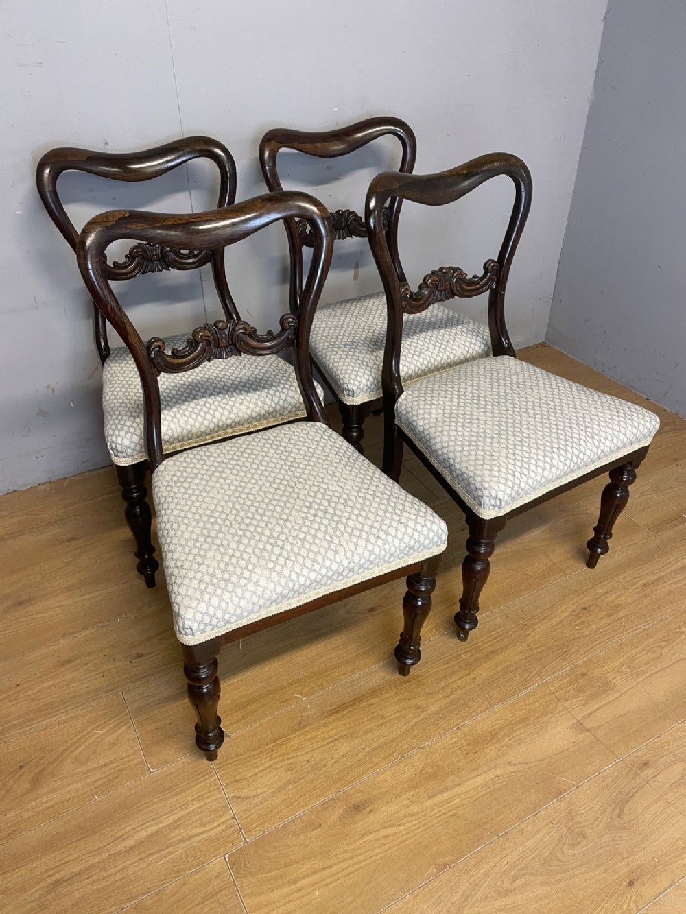 A set of four Victorian rosewood balloon back dining chairs with carved mid-rails, turned front legs, and grey patterned upholstered seats. View VII