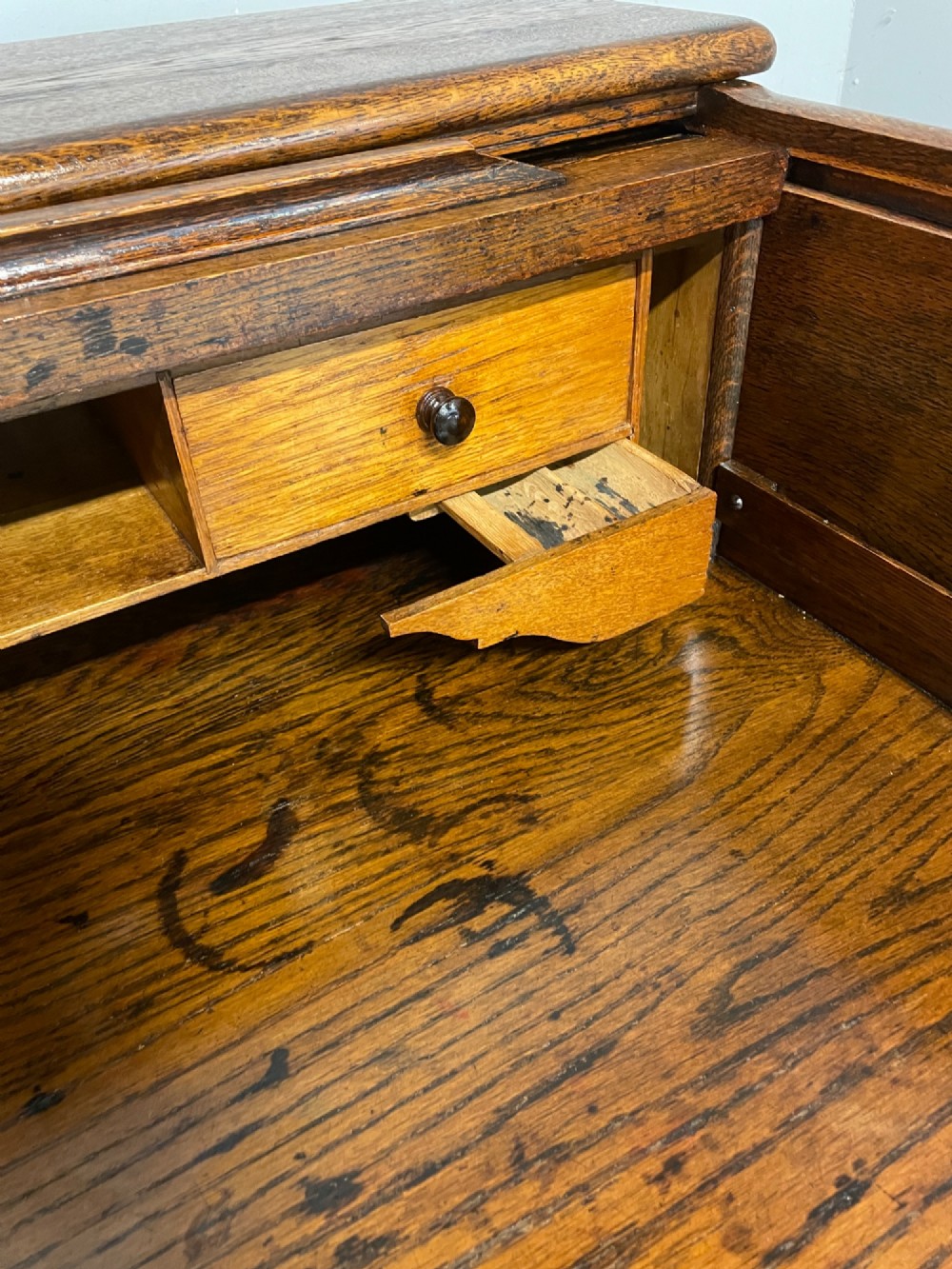 An Edwardian solid oak twin-pedestal roll top desk featuring a curved tambour front, fitted drawers with integrated wooden handles, and a central brass keyhole. View V