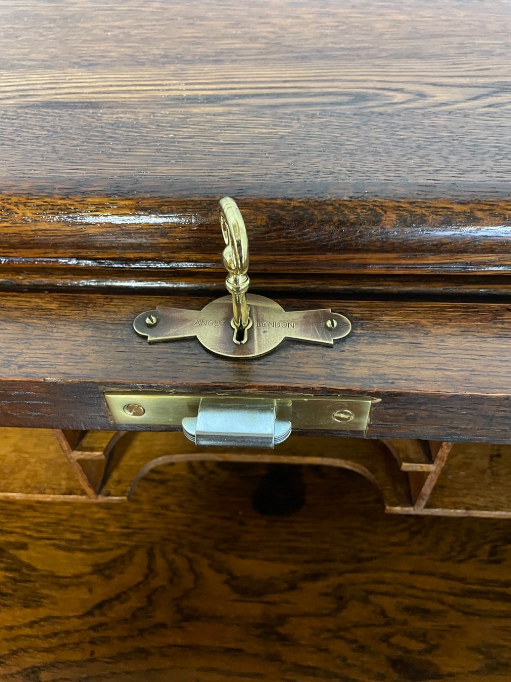 An Edwardian solid oak twin-pedestal roll top desk featuring a curved tambour front, fitted drawers with integrated wooden handles, and a central brass keyhole. View VII