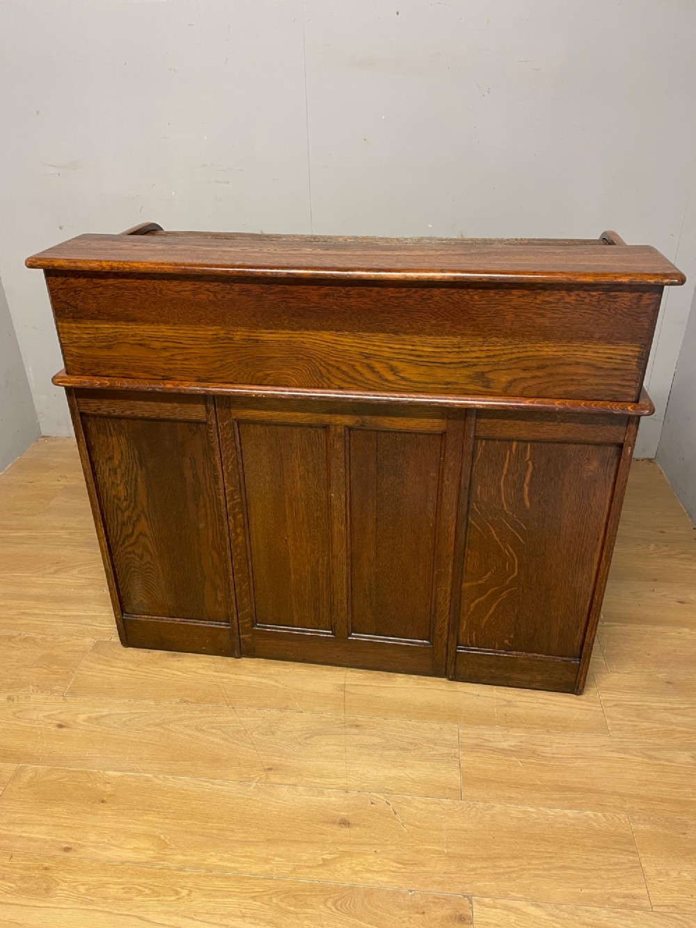 An Edwardian solid oak twin-pedestal roll top desk featuring a curved tambour front, fitted drawers with integrated wooden handles, and a central brass keyhole. View X