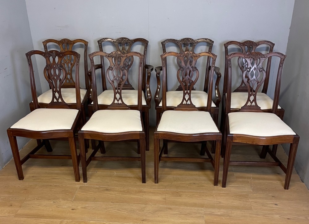 A set of eight solid mahogany Chippendale style dining chairs with intricate carved pierced splats and light cream drop-in seats.
