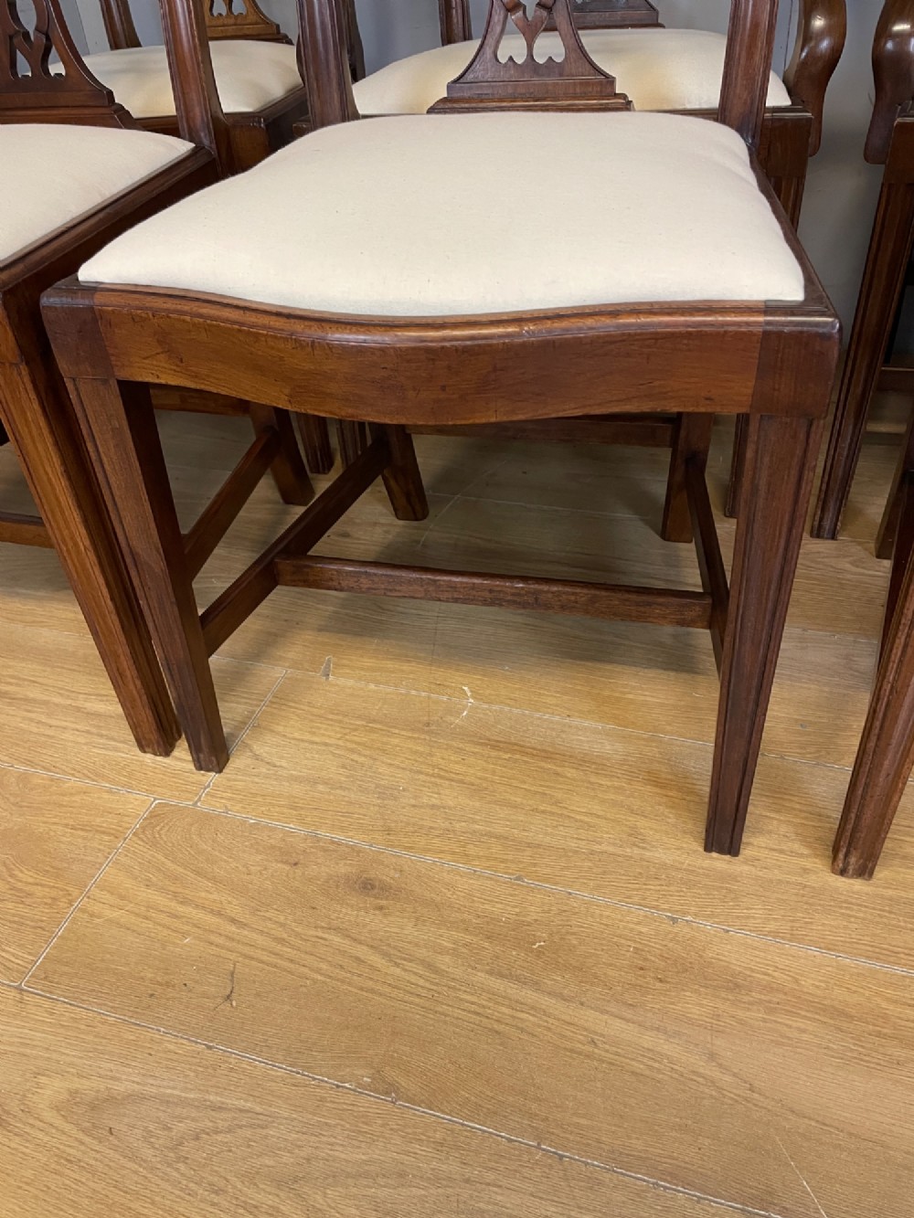 A set of eight solid mahogany Chippendale style dining chairs with intricate carved pierced splats and light cream drop-in seats. View IV
