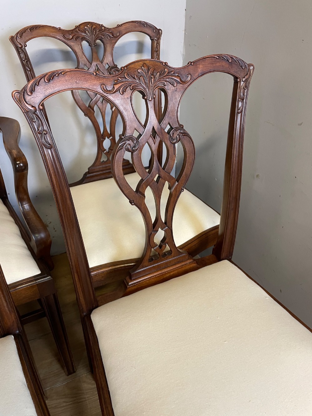 A set of eight solid mahogany Chippendale style dining chairs with intricate carved pierced splats and light cream drop-in seats. View V