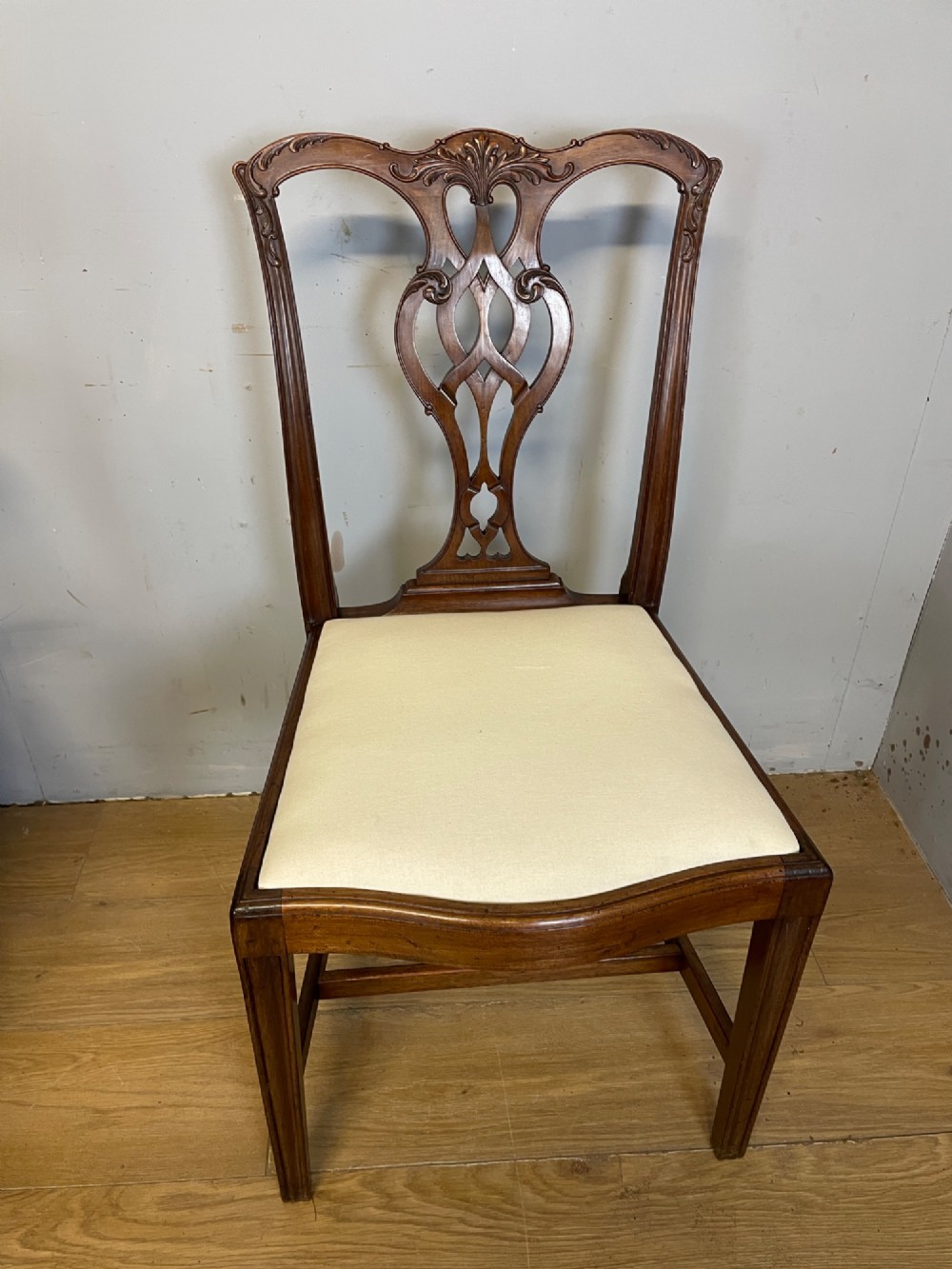 A set of eight solid mahogany Chippendale style dining chairs with intricate carved pierced splats and light cream drop-in seats. View IX