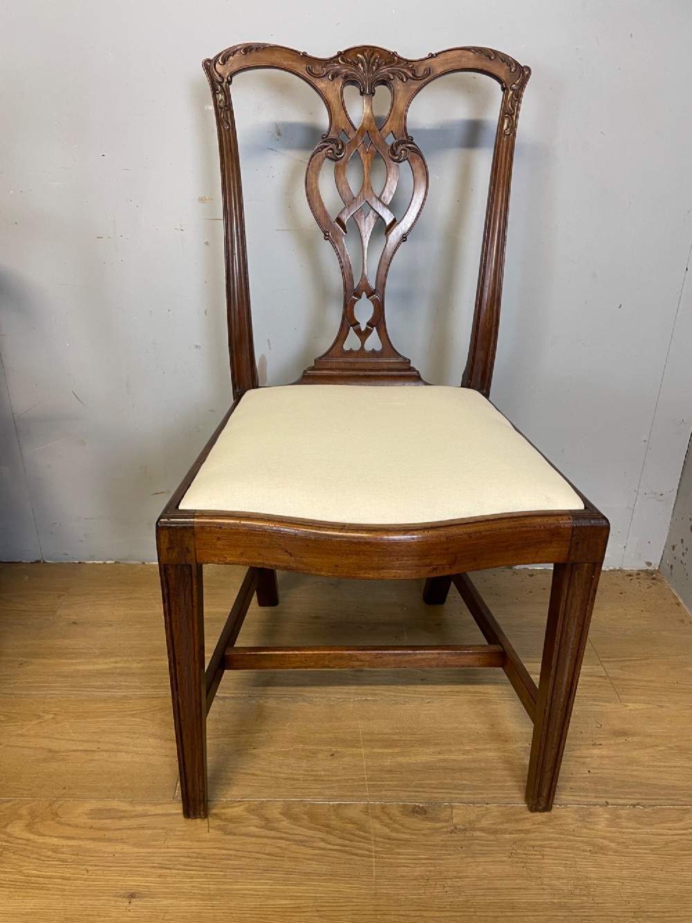 A set of eight solid mahogany Chippendale style dining chairs with intricate carved pierced splats and light cream drop-in seats. View X