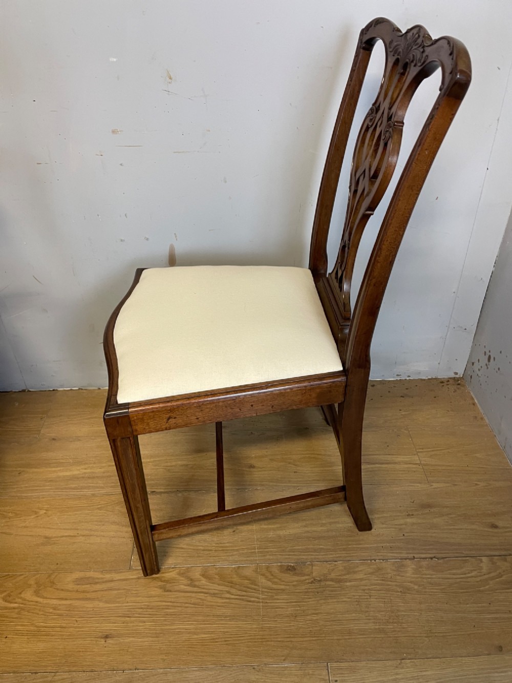 A set of eight solid mahogany Chippendale style dining chairs with intricate carved pierced splats and light cream drop-in seats. View XI