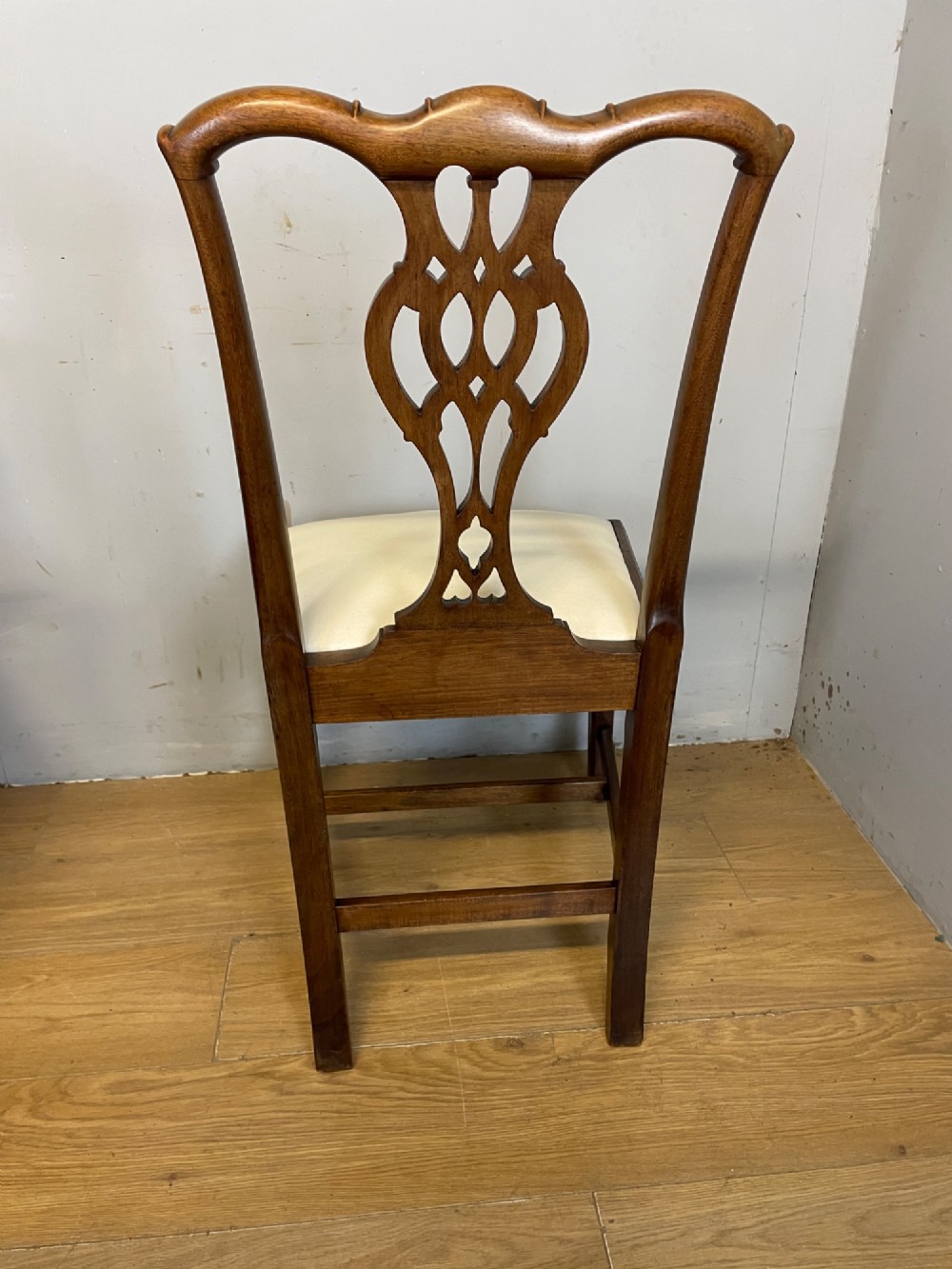 A set of eight solid mahogany Chippendale style dining chairs with intricate carved pierced splats and light cream drop-in seats. View XII