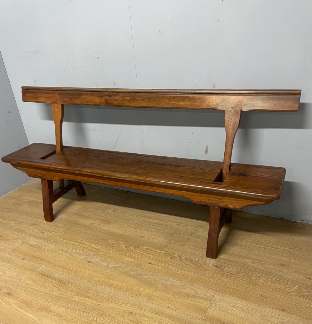 A Victorian pitch pine and mahogany bench featuring a long solid seat and a reversible swing backrest.