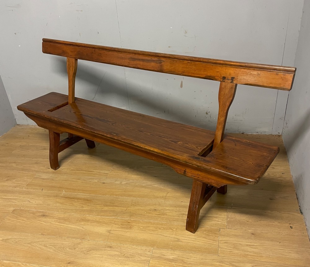 A Victorian pitch pine and mahogany bench featuring a long solid seat and a reversible swing backrest. View V