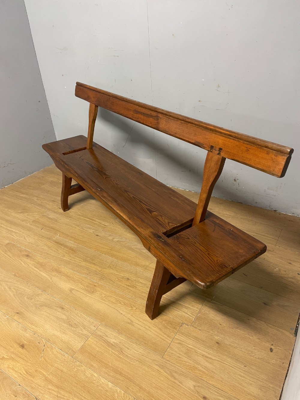 A Victorian pitch pine and mahogany bench featuring a long solid seat and a reversible swing backrest. View VI