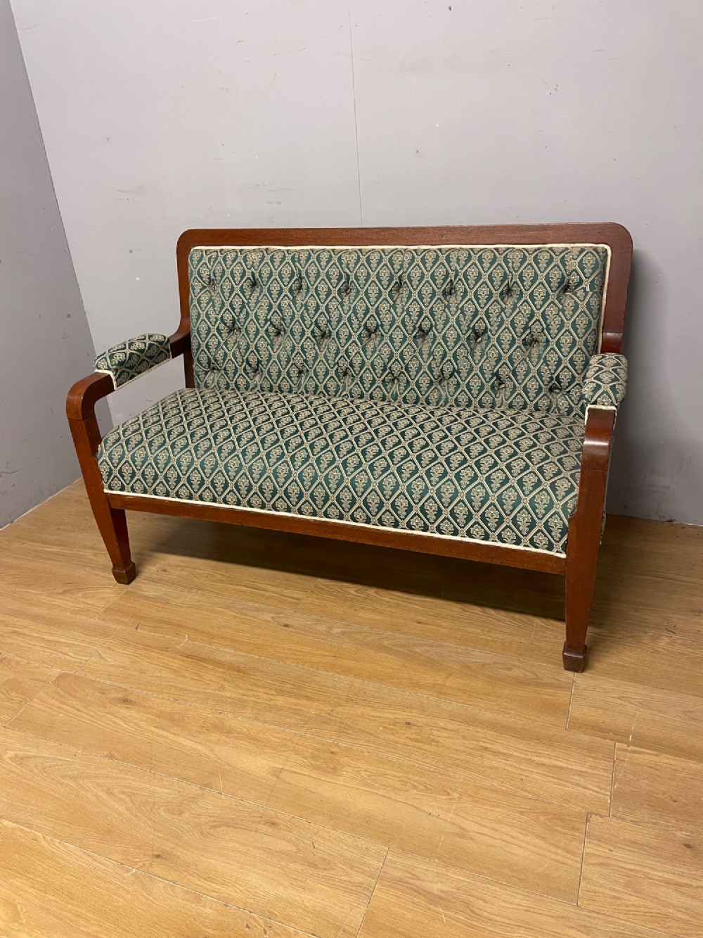 Late nineteenth-century mahogany frame two-seater sofa with deep buttoned green and cream patterned fabric upholstery.