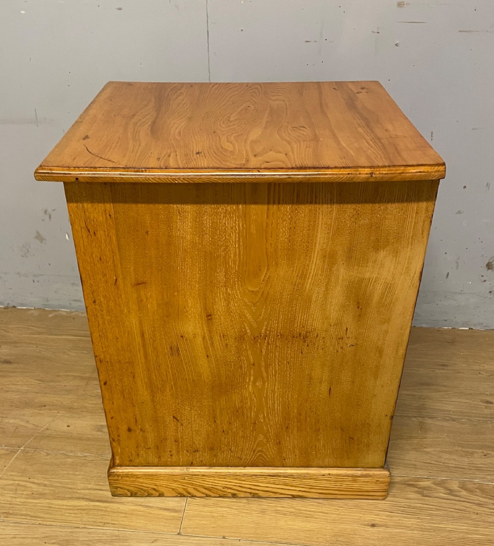 A late 19th-century small ash three-drawer chest featuring cast metal handles, brass keyhole escutcheons, a moulded edge top, and a solid plinth base. View VII