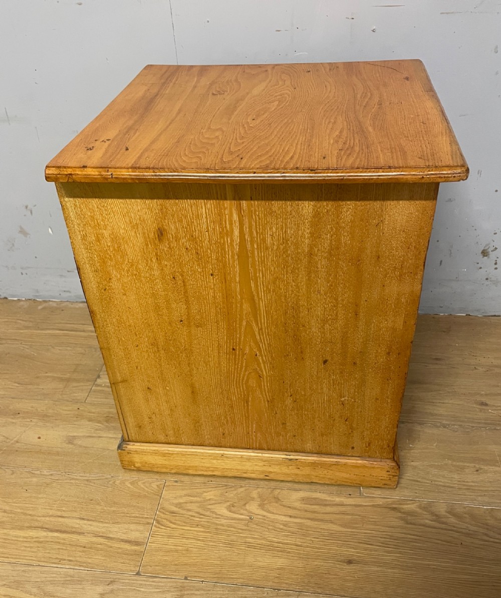 A late 19th-century small ash three-drawer chest featuring cast metal handles, brass keyhole escutcheons, a moulded edge top, and a solid plinth base. View IX