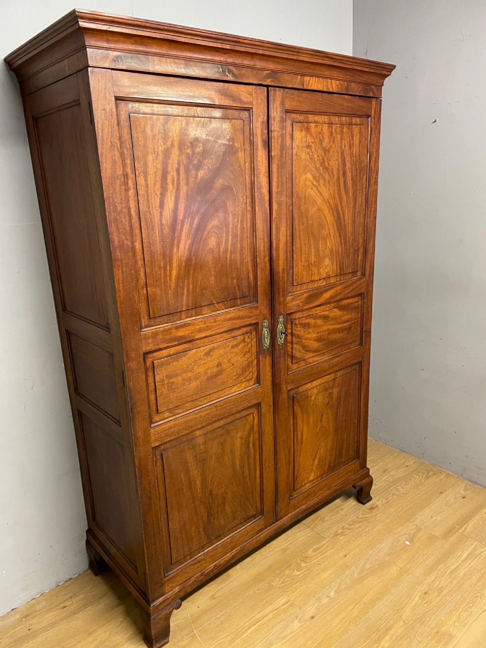 A nineteenth-century two-door flame mahogany wardrobe with panelled doors, brass escutcheons, and a moulded cornice. View III