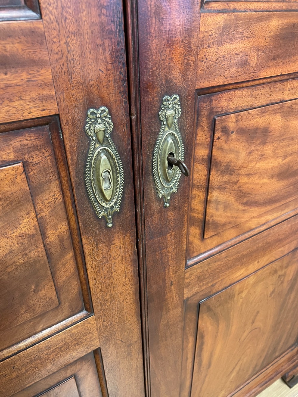 A nineteenth-century two-door flame mahogany wardrobe with panelled doors, brass escutcheons, and a moulded cornice. View IV