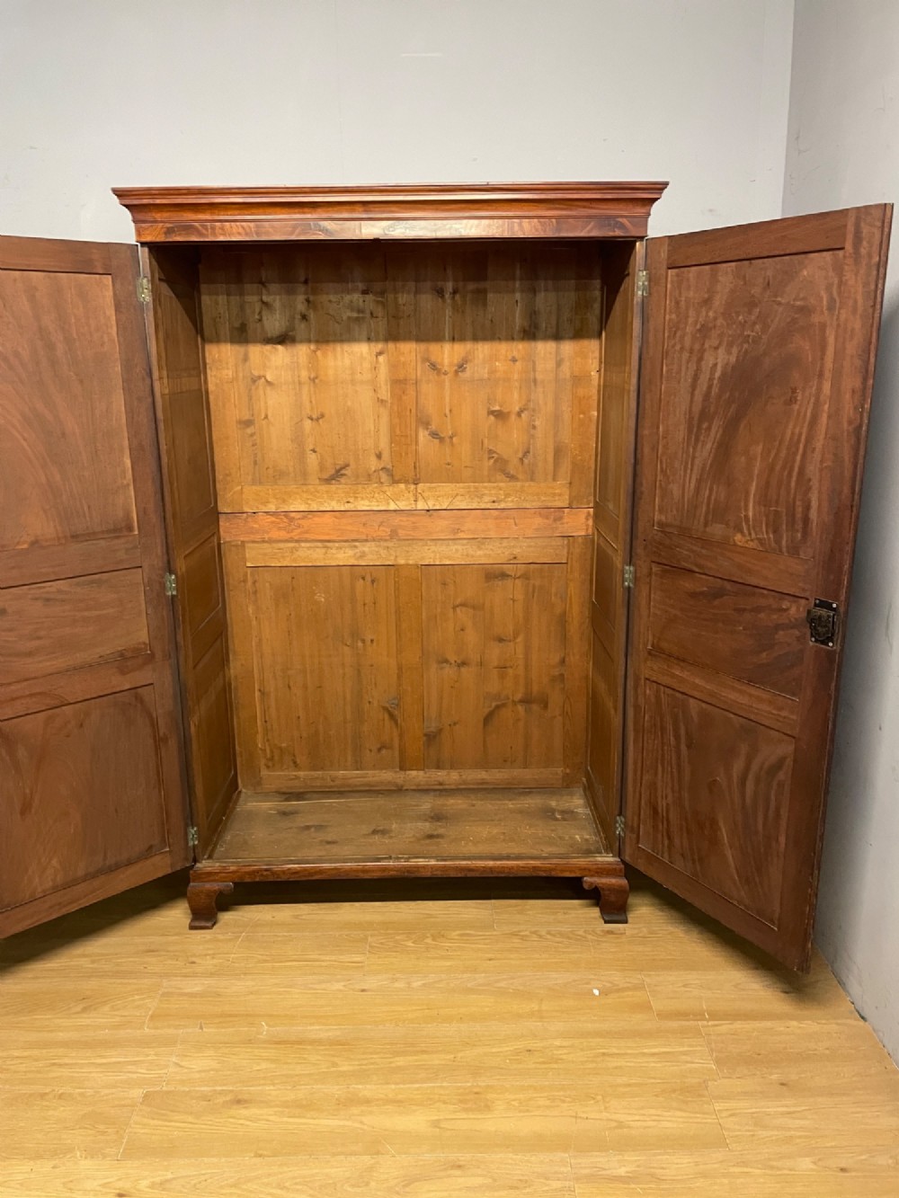 A nineteenth-century two-door flame mahogany wardrobe with panelled doors, brass escutcheons, and a moulded cornice. View VII