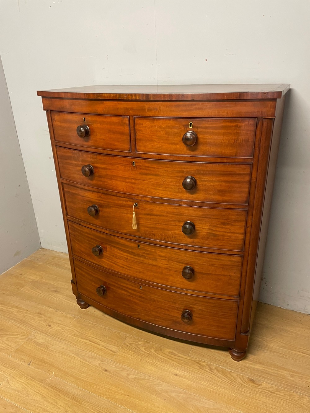 A 19th-century mahogany bow front chest of drawers featuring two short drawers over three long drawers with turned wooden handles. View II