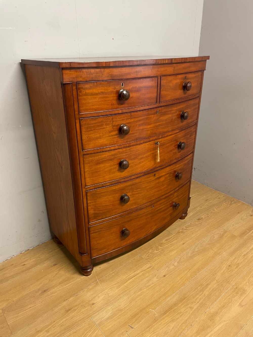 A 19th-century mahogany bow front chest of drawers featuring two short drawers over three long drawers with turned wooden handles. View III