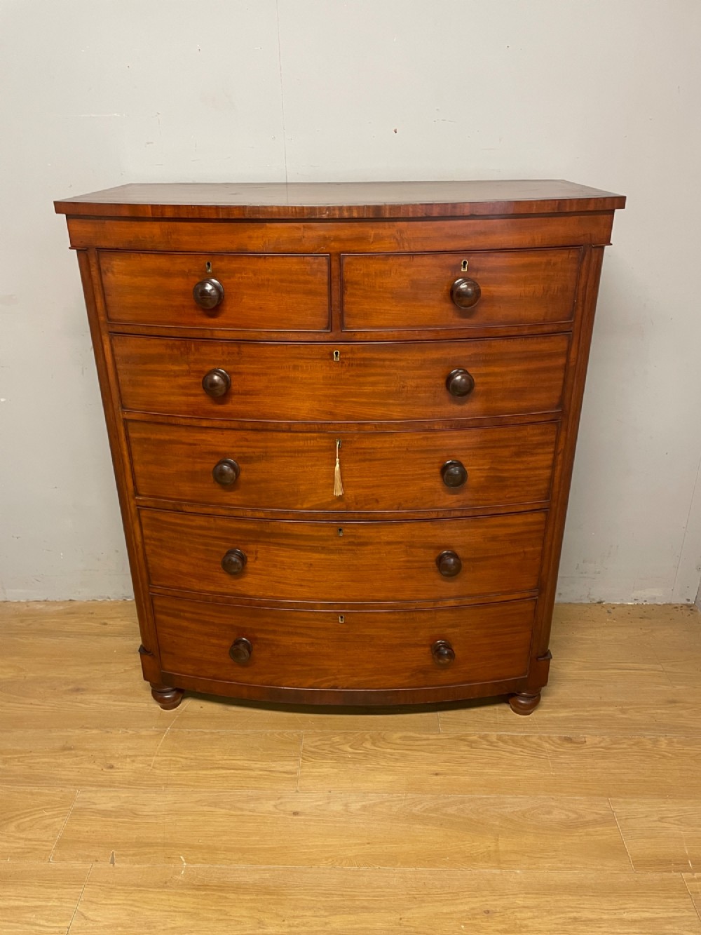 A 19th-century mahogany bow front chest of drawers featuring two short drawers over three long drawers with turned wooden handles. View IV