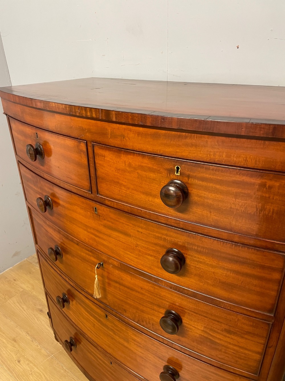 A 19th-century mahogany bow front chest of drawers featuring two short drawers over three long drawers with turned wooden handles. View V