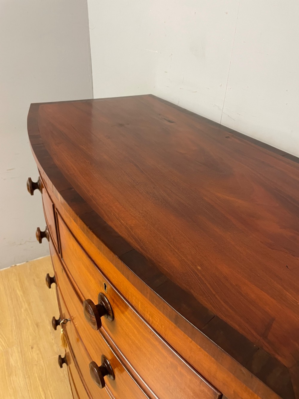 A 19th-century mahogany bow front chest of drawers featuring two short drawers over three long drawers with turned wooden handles. View VI