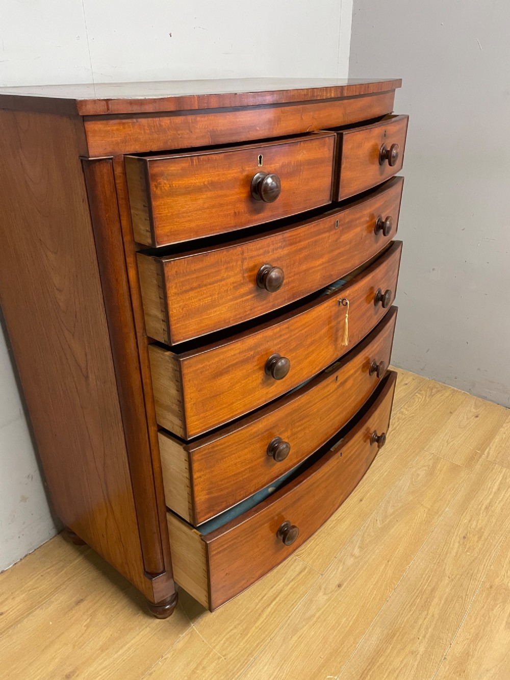 A 19th-century mahogany bow front chest of drawers featuring two short drawers over three long drawers with turned wooden handles. View VIII