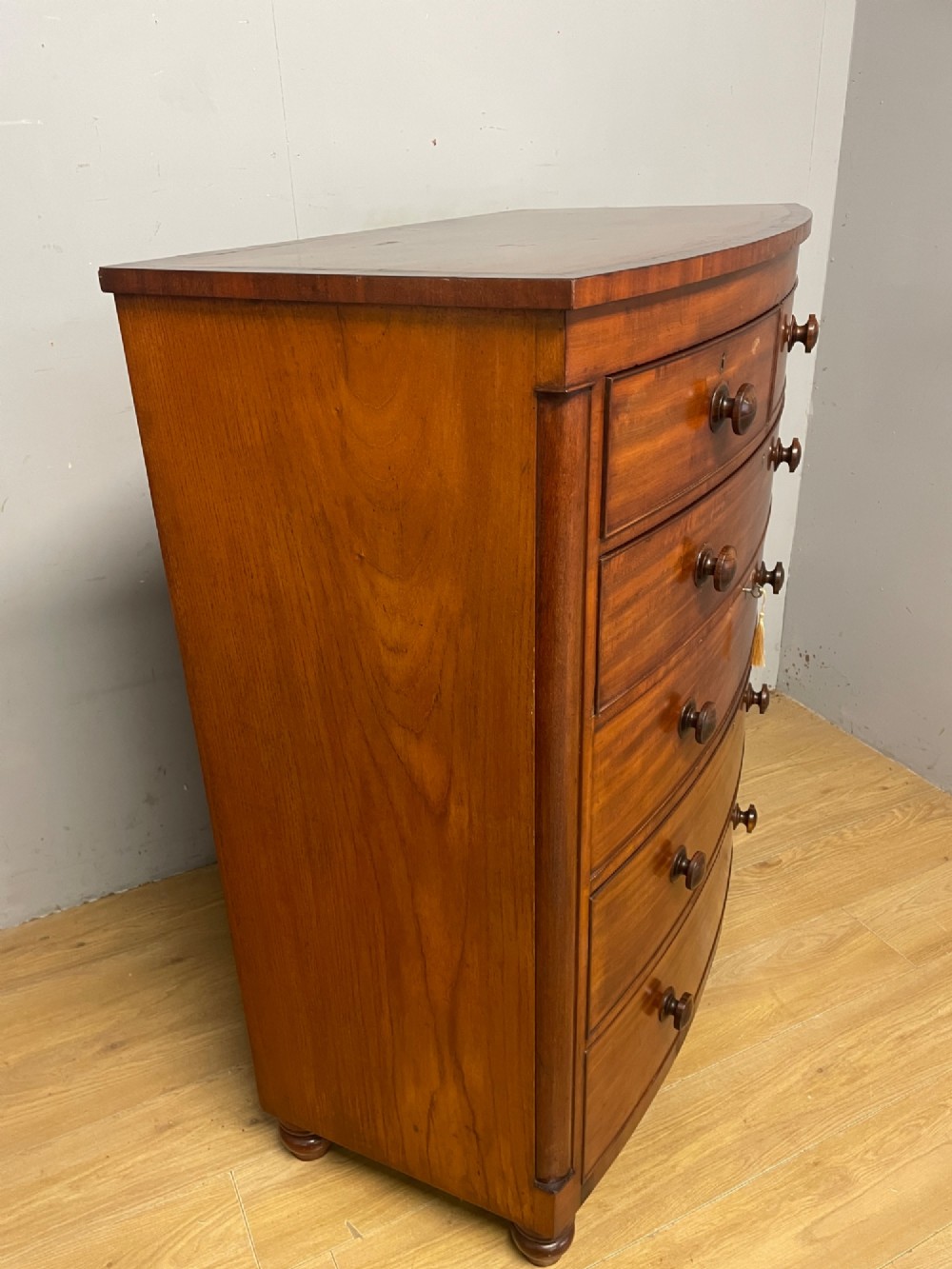 A 19th-century mahogany bow front chest of drawers featuring two short drawers over three long drawers with turned wooden handles. View XI