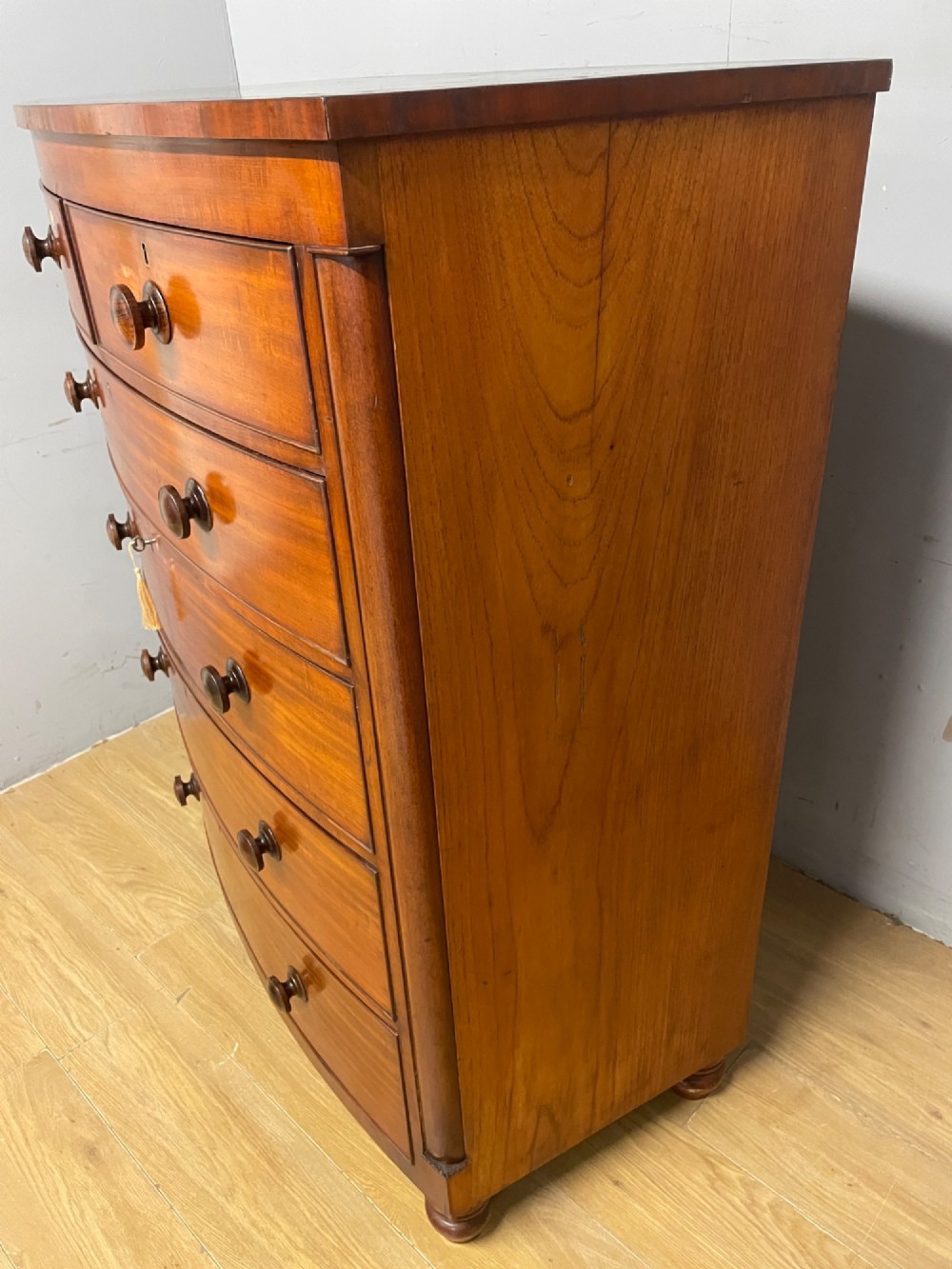 A 19th-century mahogany bow front chest of drawers featuring two short drawers over three long drawers with turned wooden handles. View XIII