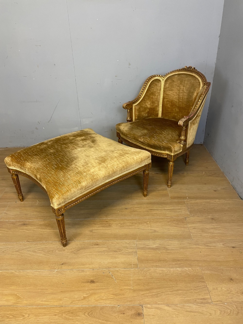 An Edwardian carved giltwood armchair with a matching rectangular footstool upholstered in gold velvet. View V