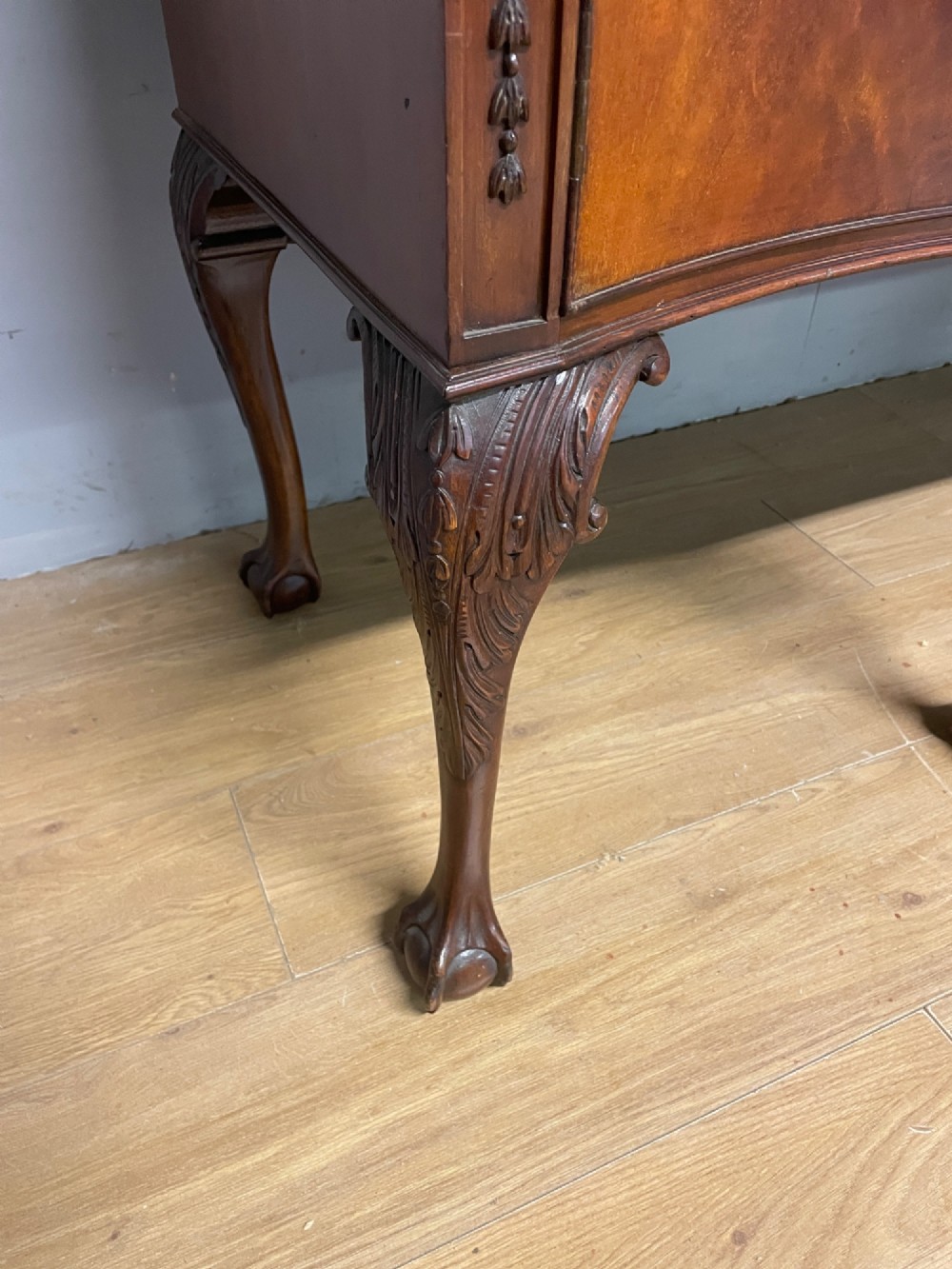 A late 19th-century flame mahogany Chippendale revival sideboard featuring carved cabriole legs with ball-and-claw feet, serpentine front drawers, and brass ring handles. View V