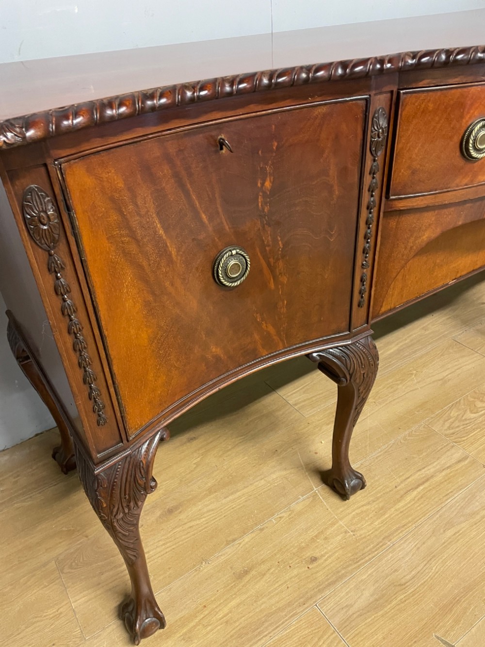 A late 19th-century flame mahogany Chippendale revival sideboard featuring carved cabriole legs with ball-and-claw feet, serpentine front drawers, and brass ring handles. View VI
