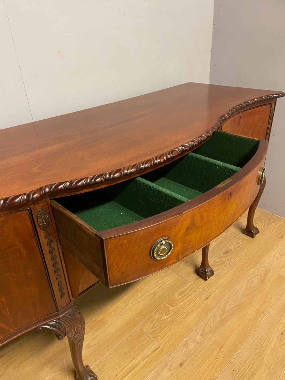 A late 19th-century flame mahogany Chippendale revival sideboard featuring carved cabriole legs with ball-and-claw feet, serpentine front drawers, and brass ring handles. View VII