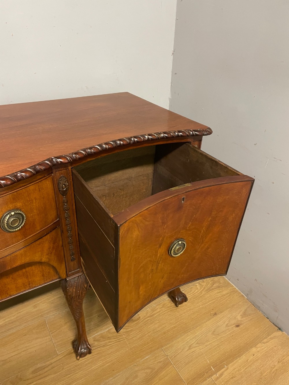 A late 19th-century flame mahogany Chippendale revival sideboard featuring carved cabriole legs with ball-and-claw feet, serpentine front drawers, and brass ring handles. View IX