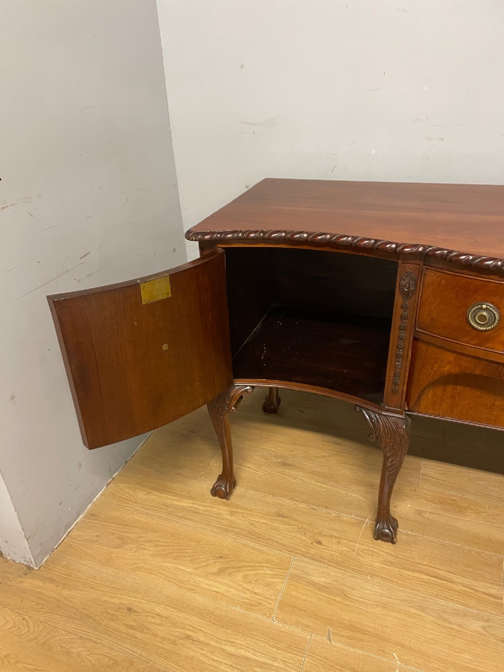 A late 19th-century flame mahogany Chippendale revival sideboard featuring carved cabriole legs with ball-and-claw feet, serpentine front drawers, and brass ring handles. View X