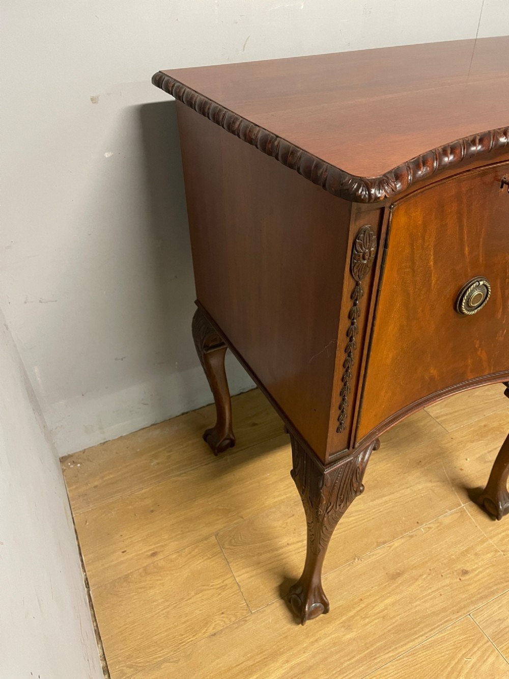 A late 19th-century flame mahogany Chippendale revival sideboard featuring carved cabriole legs with ball-and-claw feet, serpentine front drawers, and brass ring handles. View XI