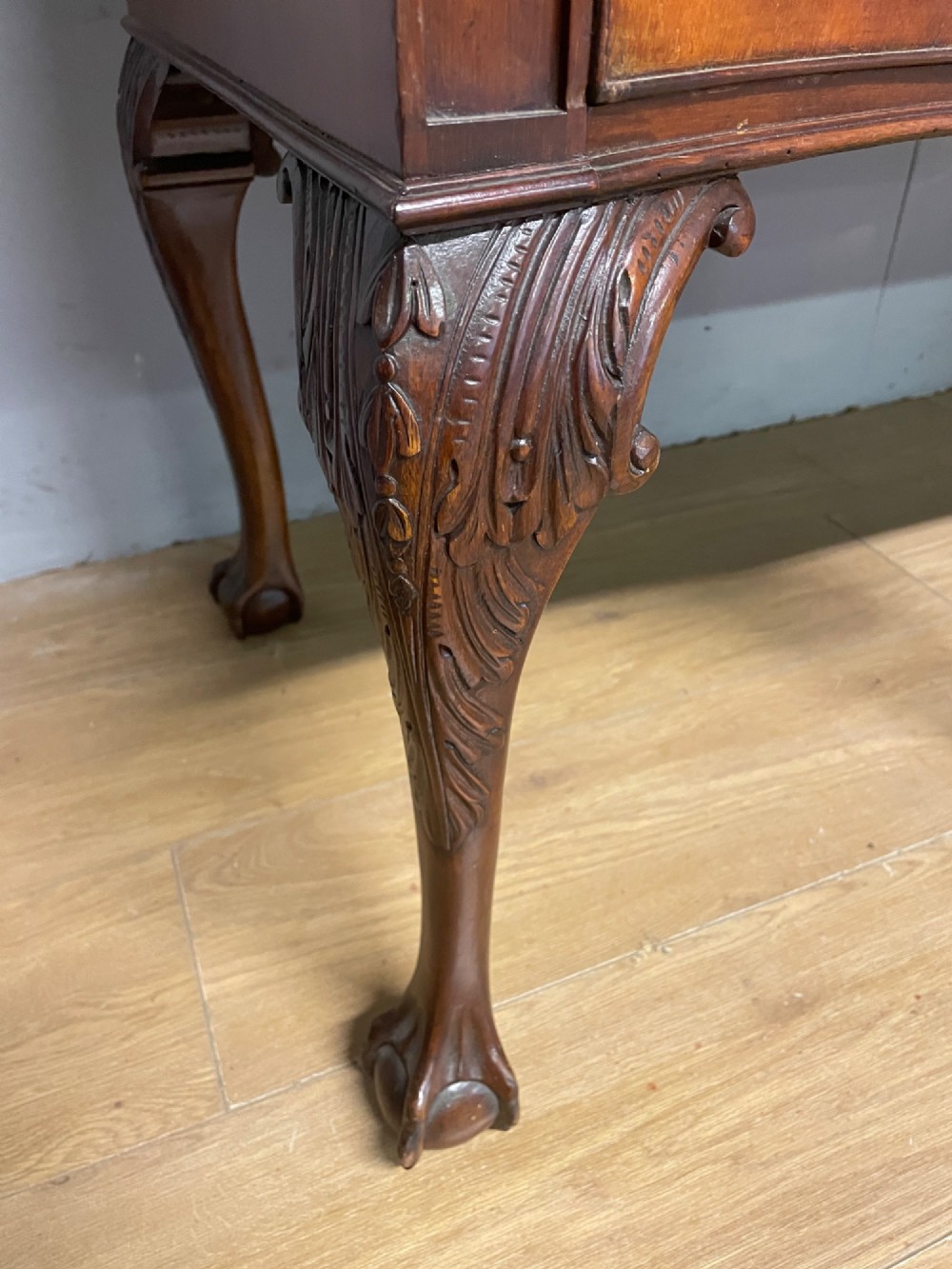 A late 19th-century flame mahogany Chippendale revival sideboard featuring carved cabriole legs with ball-and-claw feet, serpentine front drawers, and brass ring handles. View XII