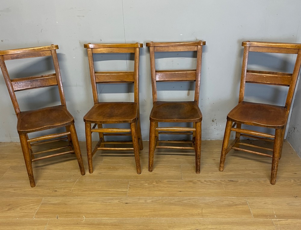 A set of four late nineteenth-century wooden chapel chairs featuring solid elm seats, open backrests with integrated bible troughs, and sturdy stretchers. View II