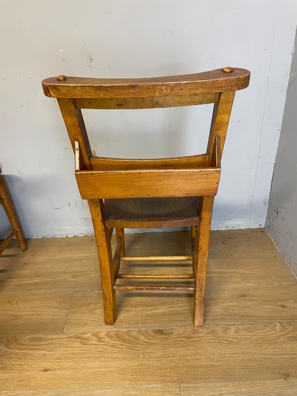A set of four late nineteenth-century wooden chapel chairs featuring solid elm seats, open backrests with integrated bible troughs, and sturdy stretchers. View VIII